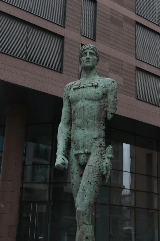 a large bronze statue stands next to a brick building