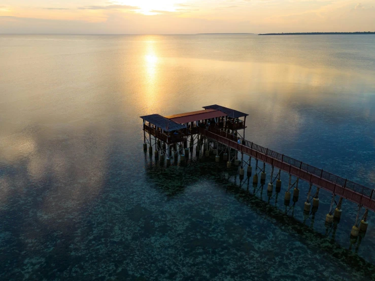 an ocean pier next to a body of water at sunset