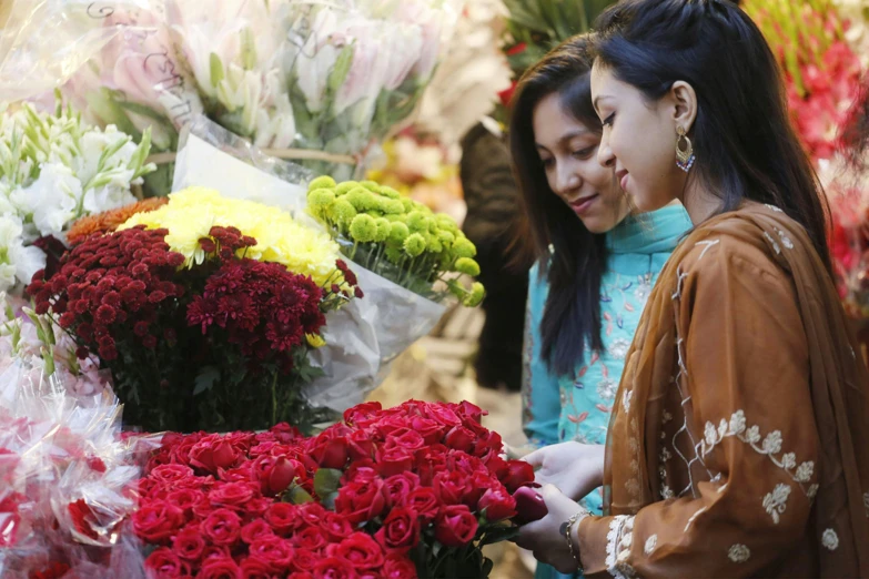 a woman standing behind a display of red, yellow and white flowers