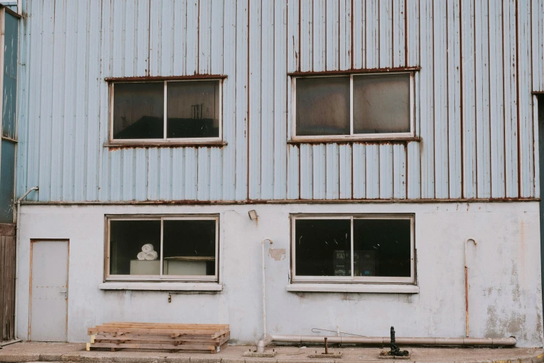 an old blue building with two windows that are closed