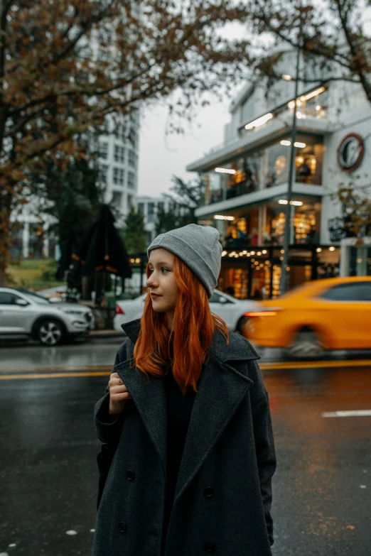 a woman with red hair is walking in the rain