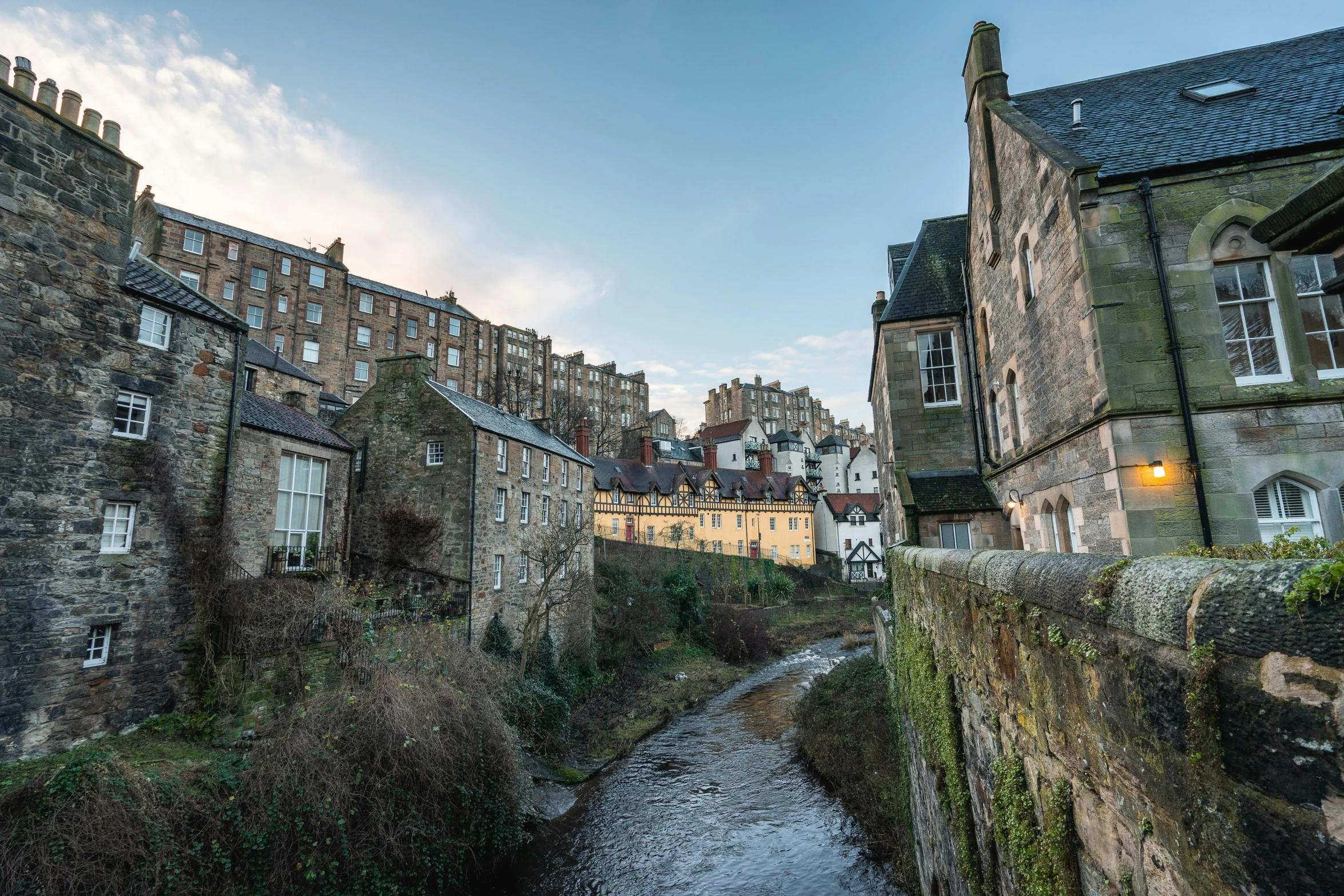 a river flowing through a small town next to old stone buildings