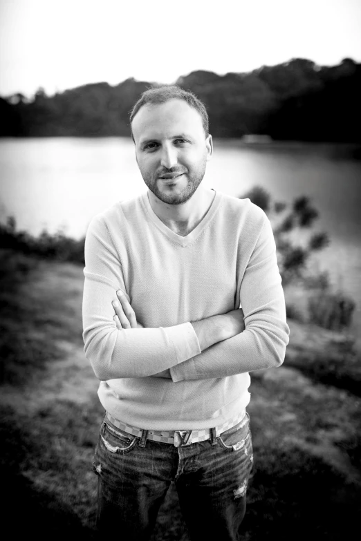 a man is standing in a grassy area next to water