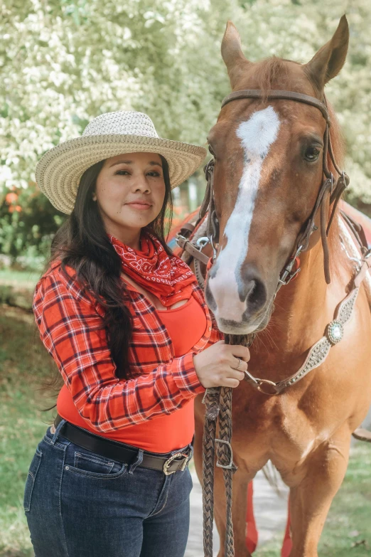 woman posing with horse wearing cowboy hat and scarf