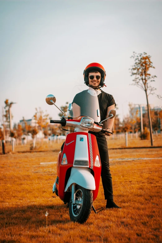 a man standing next to his moped in the grass