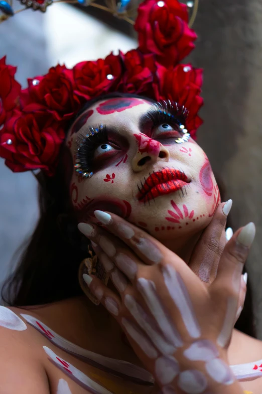 a woman in painted make up poses with flowers on her head