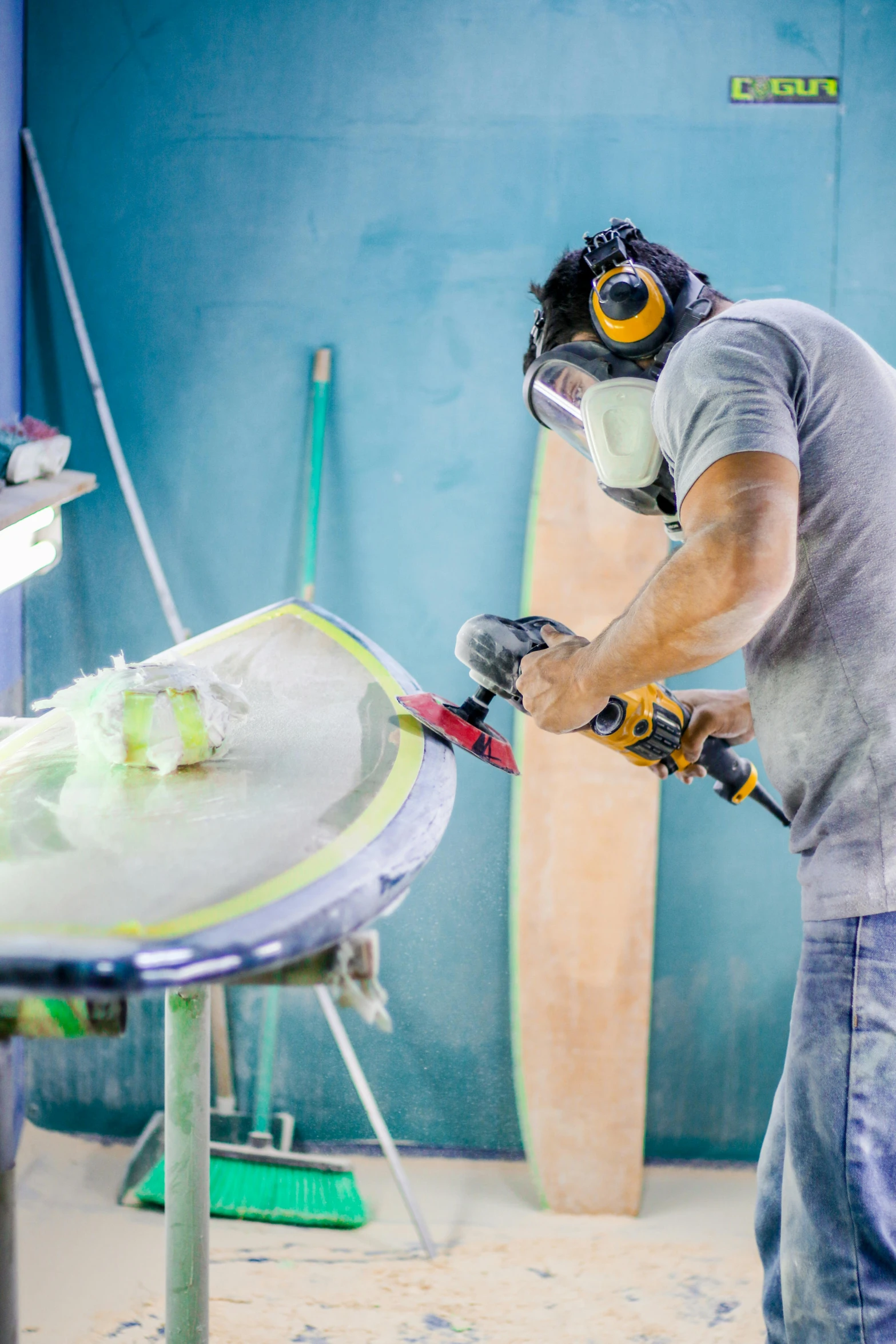 a man uses a sanding board to grind off the side of his surfboard