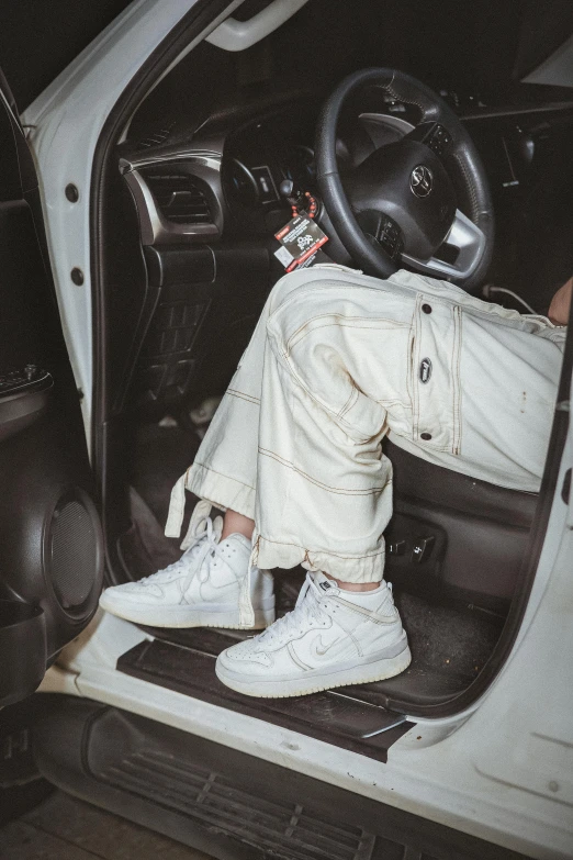 a man in white shoes sitting inside of a car