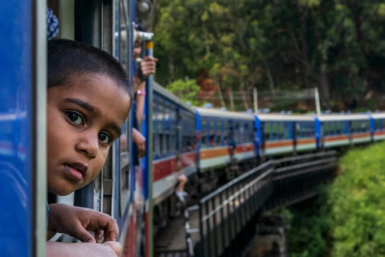 a little boy leaning against a train as it passes over the tracks