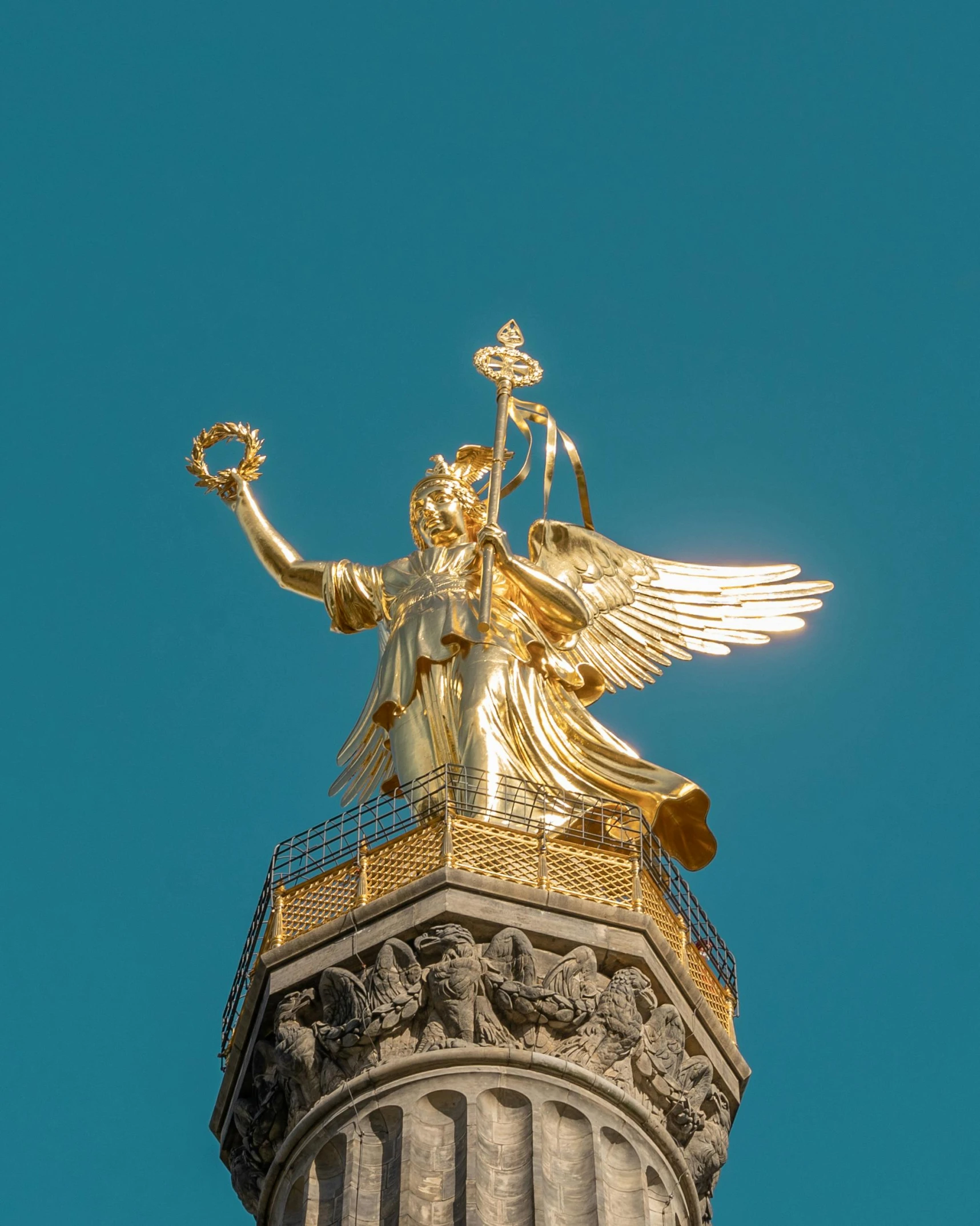 the golden statue is above a tall white pillar