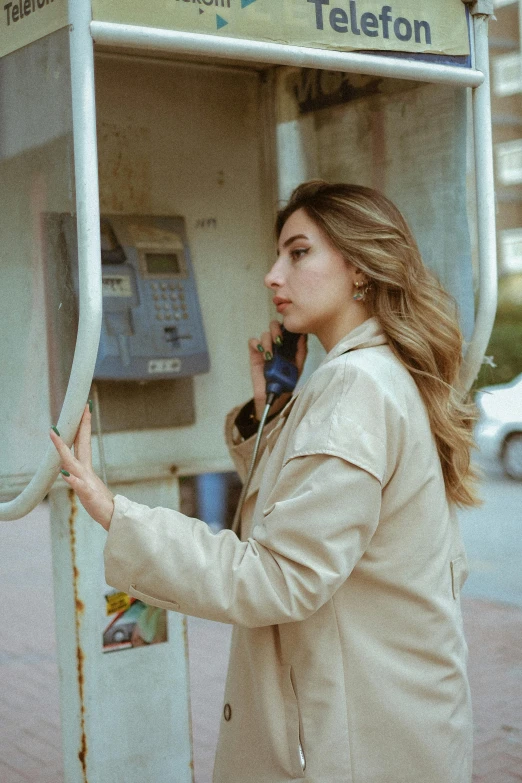 a woman talking on a cell phone near an old - fashioned telephone booth