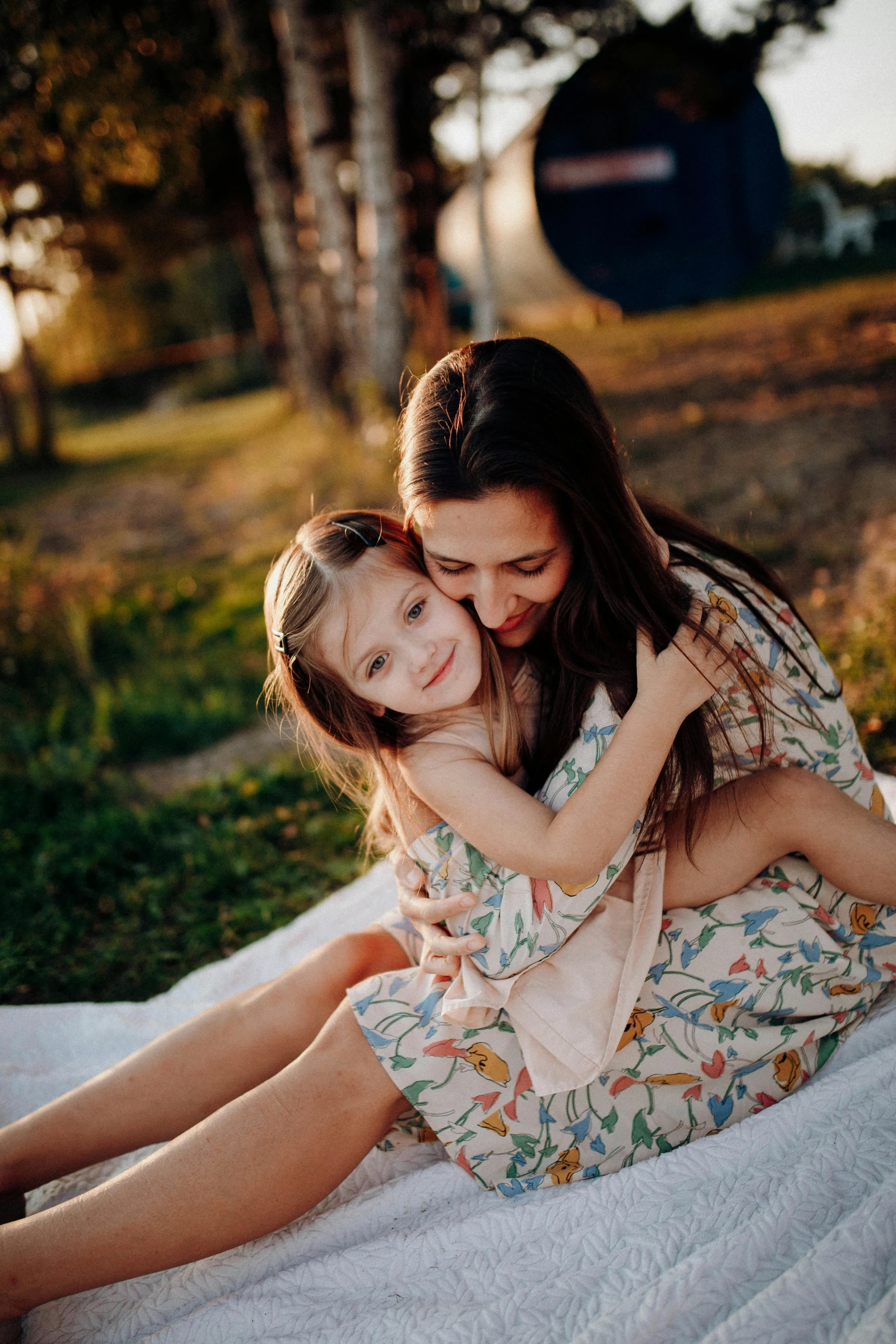 a woman sits with her little girl in her lap on the ground