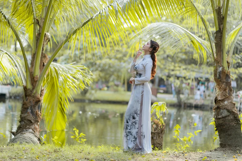 a woman in an elegant white dress standing in front of a tree