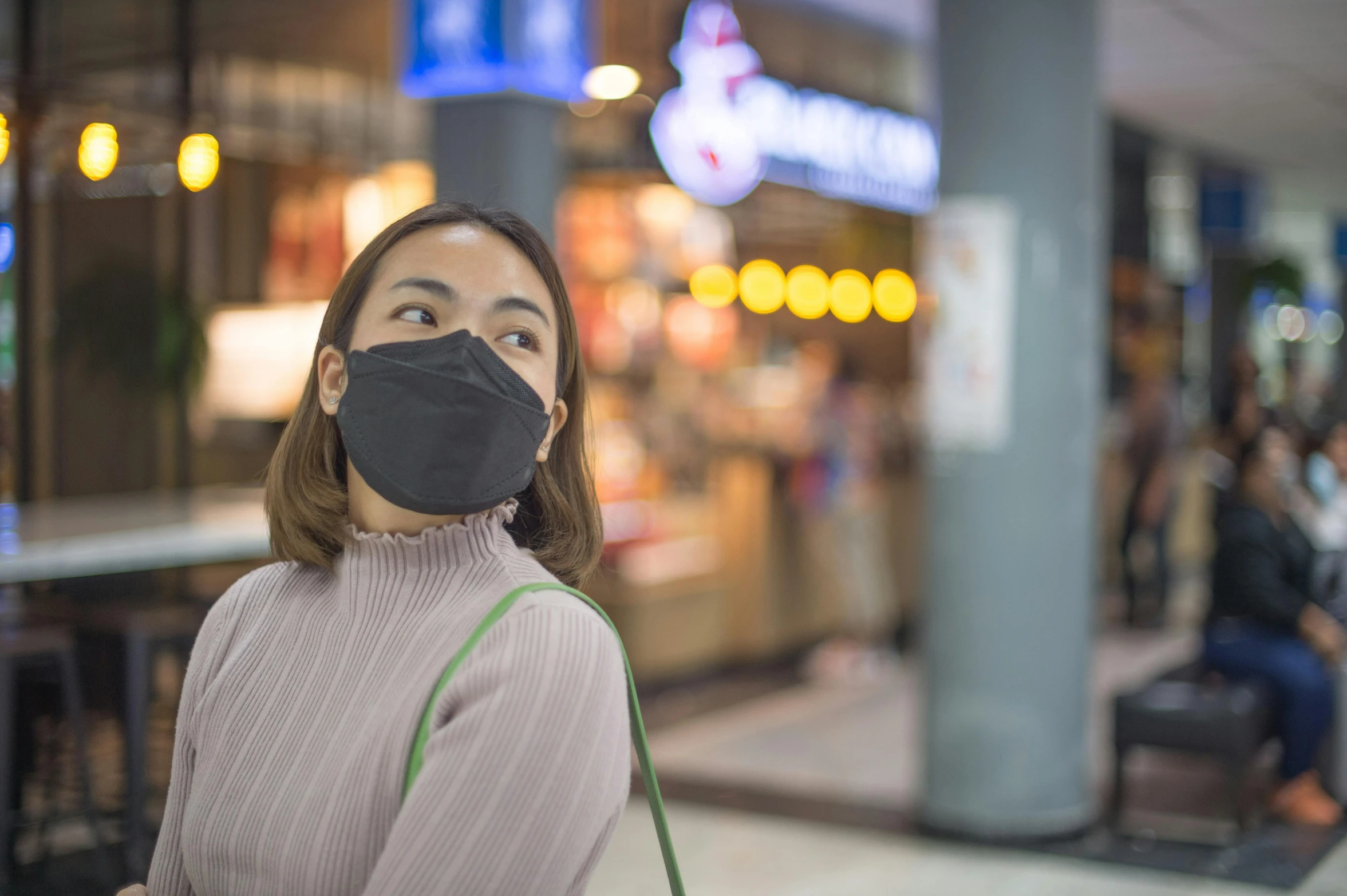 woman with black face mask looks up