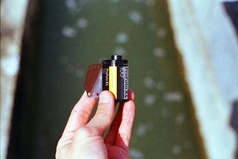 a hand holds two batteries in front of a body of water