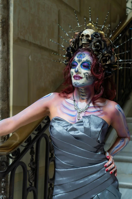 a woman in grey dress with face paint standing outside