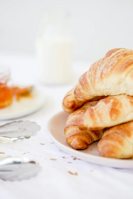 croissants on a white plate next to orange juice