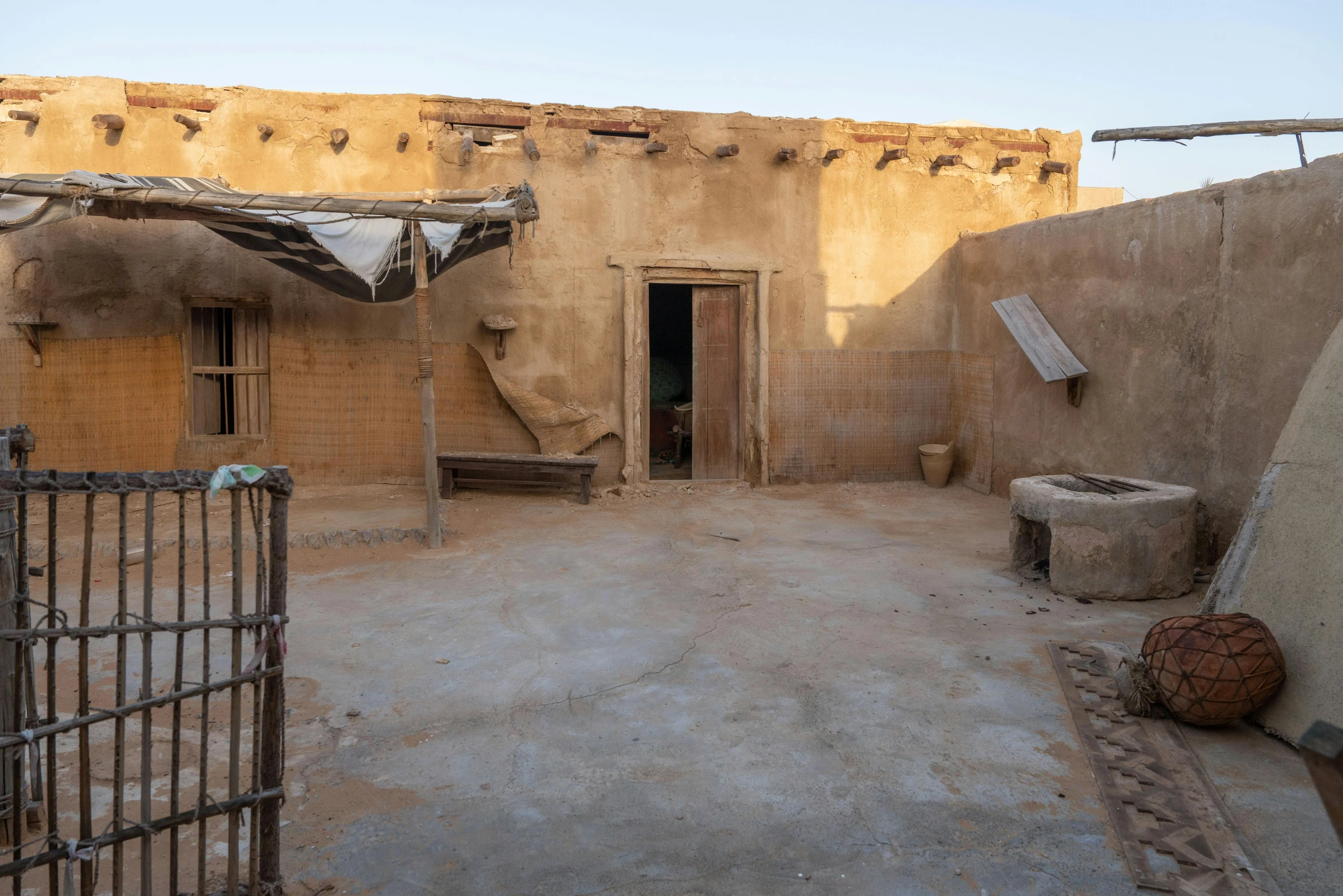 some brown walls dirt a gate and some brown building