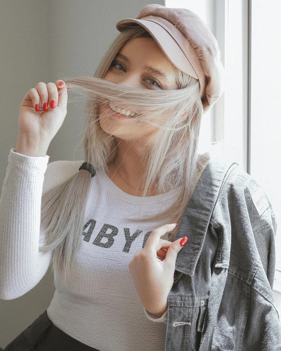 a woman with grey hair and white shirt holding scissors to her head