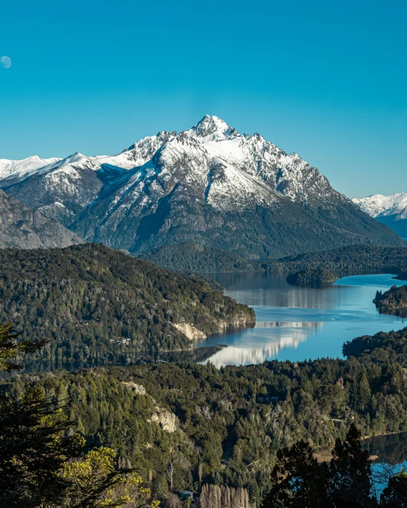 some mountains and a lake with trees and blue sky