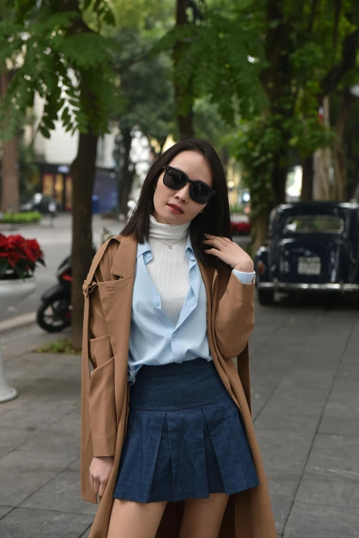 a woman wearing a trench coat and skirt standing outside