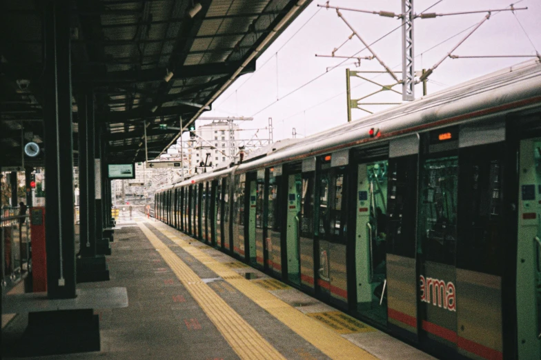 a red and green train stopped at the platform of a station