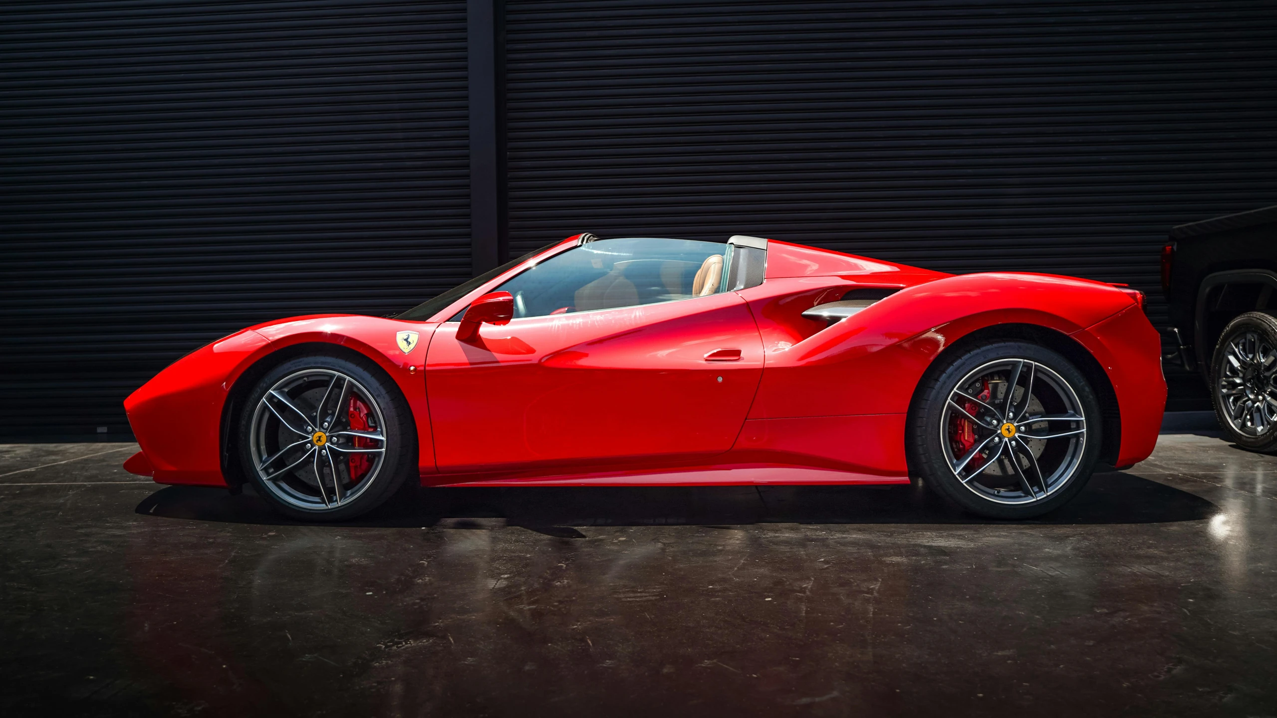 the red ferrari sports car in front of a black wall