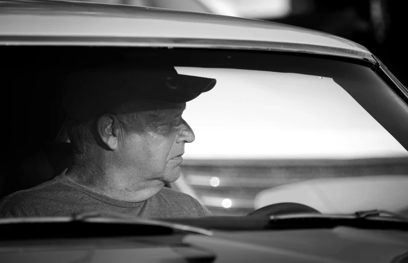 black and white image of a man looking out the back window