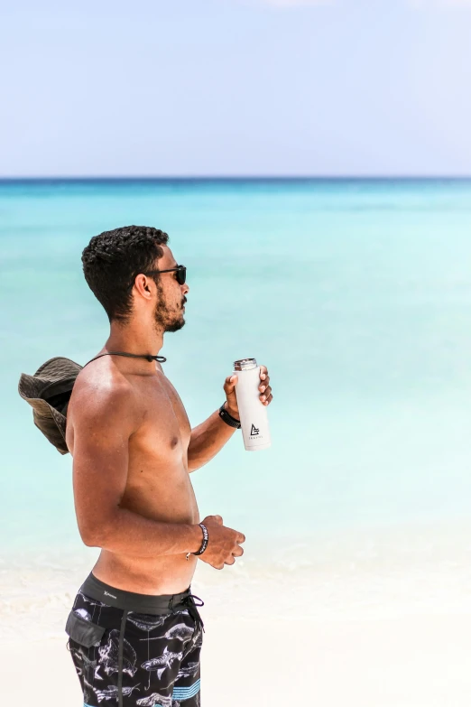 man holding a coffee cup while standing on the beach