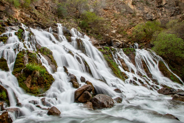 water cascading down the side of a cliff and a waterfall with trees on either side