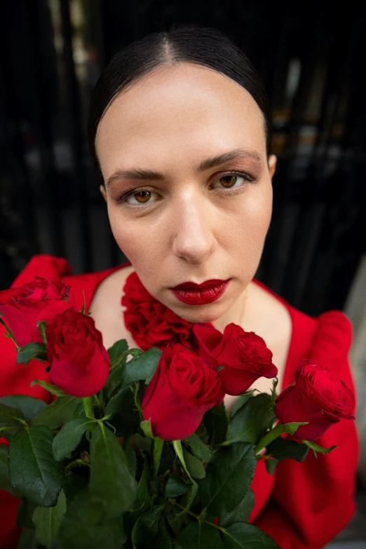 a woman in a red dress is holding two roses