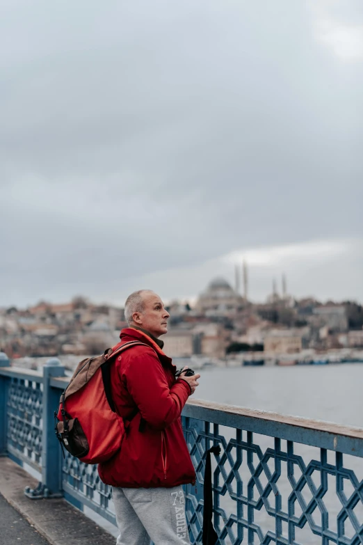 a man standing next to the water with a red backpack on