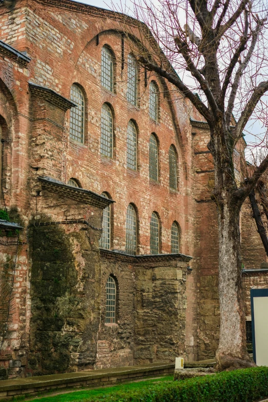 a brick building with many windows next to a tree