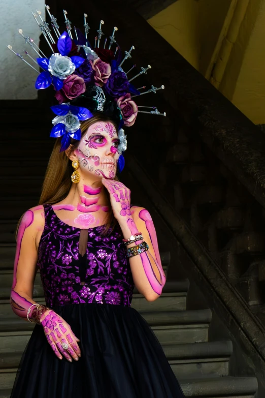 an artistically colored model posing in front of stairs with roses and nches