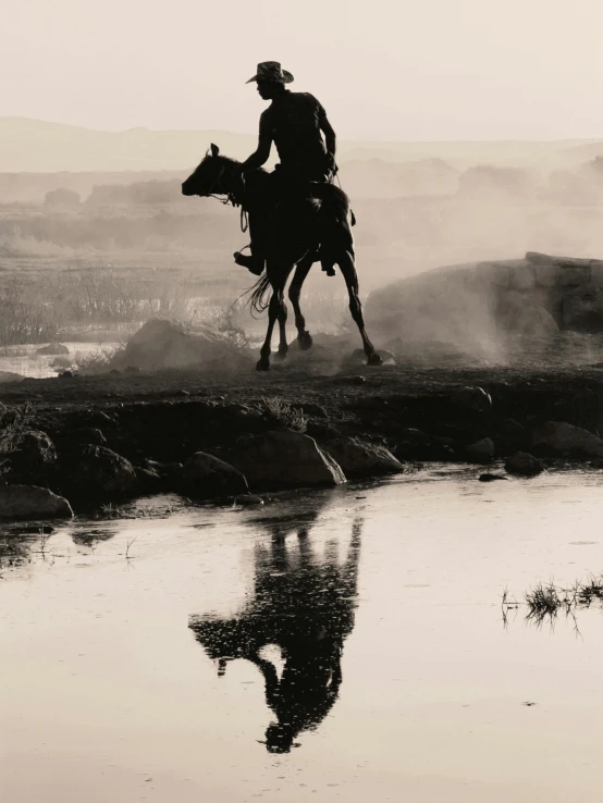 a cowboy riding on the back of a horse in a western country setting