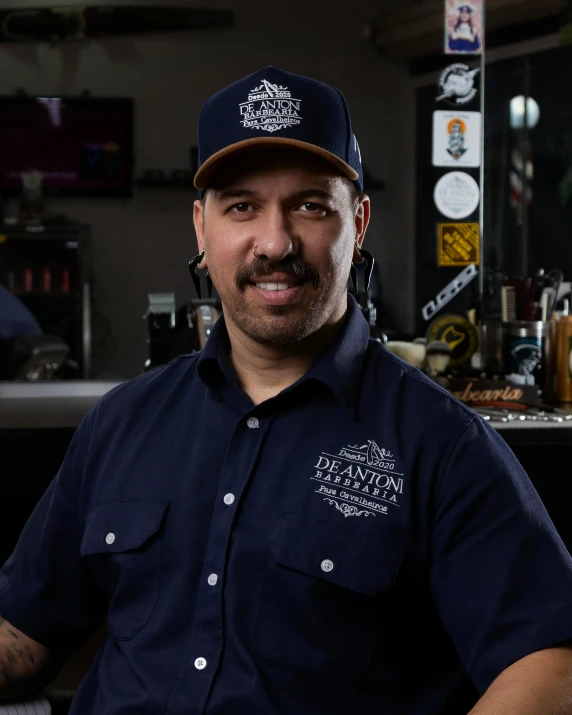 a man with a hat that says the world's greatest barbequer in front of a bar