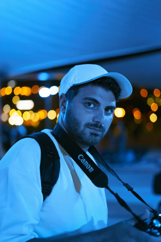 a man in a hat with a camera and blue light in the background