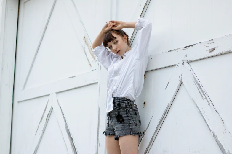 woman leaning against wall holding her hair in her hand