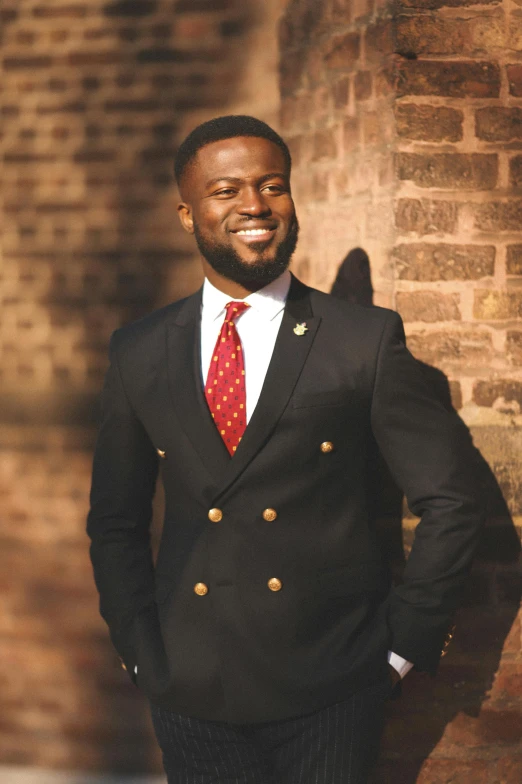 a man wearing a red tie standing next to a brick wall