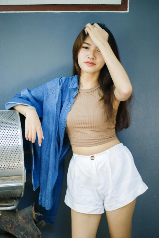 a beautiful young lady holding her jacket on while leaning against a wall