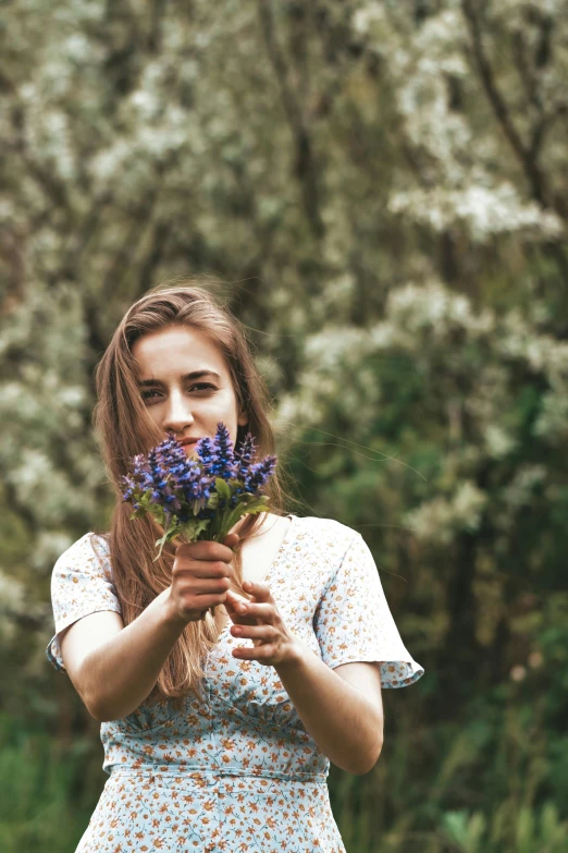 the girl in a dress is holding flowers