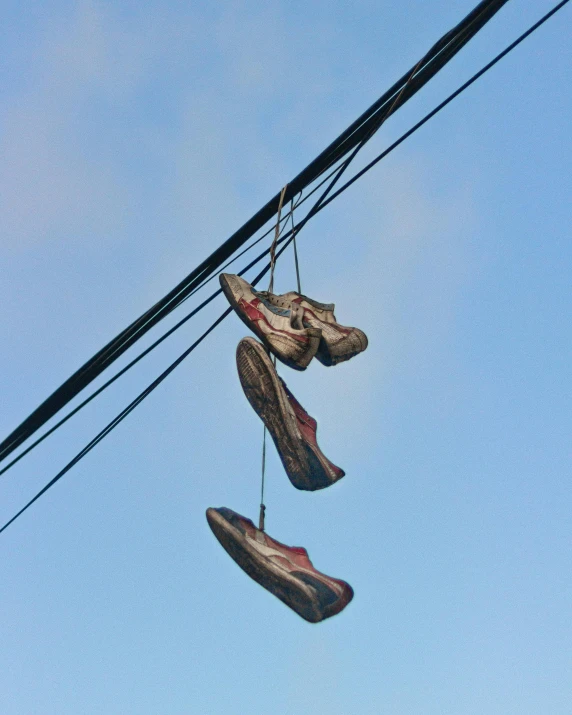 several pair of shoes hanging on a power pole