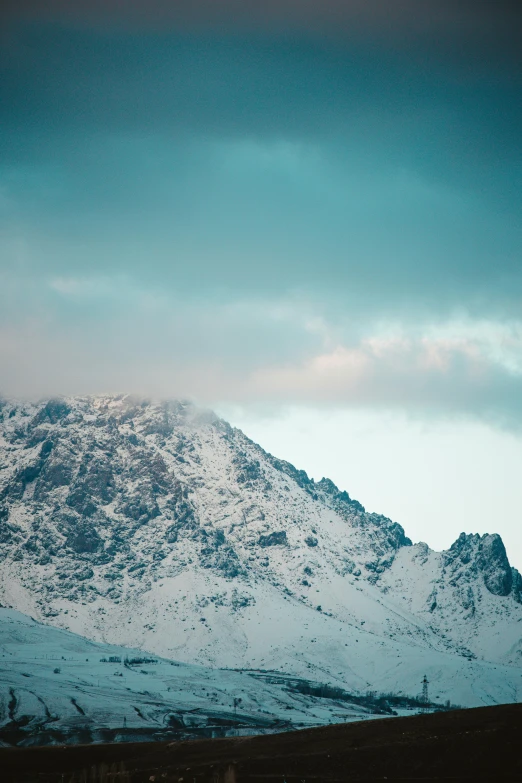 a snowy mountain with snow on it, against a sky