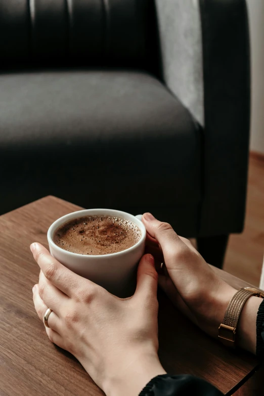 a woman holds a cup of  cocoa on her coffee table