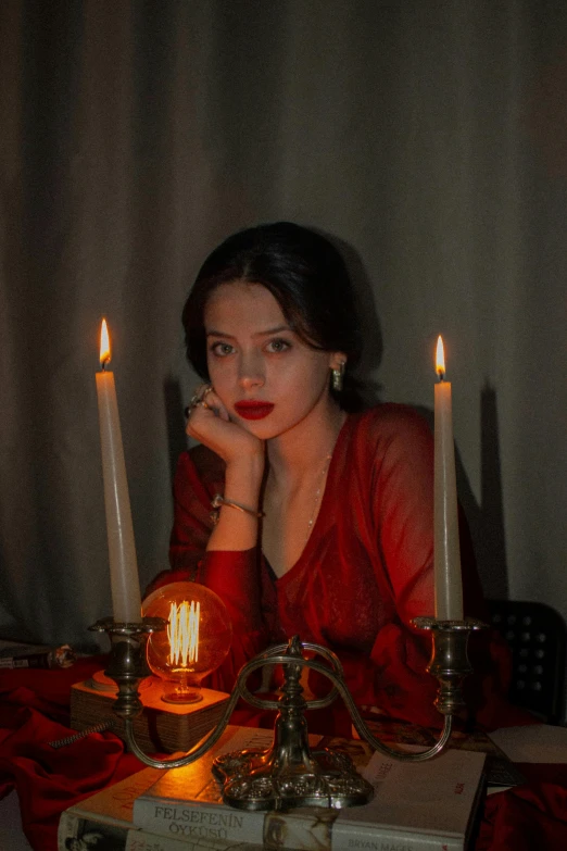 a woman is sitting at a table surrounded by candles