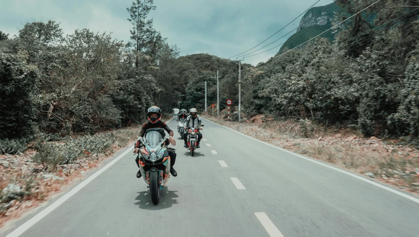 a group of men riding motorcycles on a road