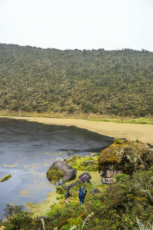 there is a group of people walking up the hill to a mountain lake