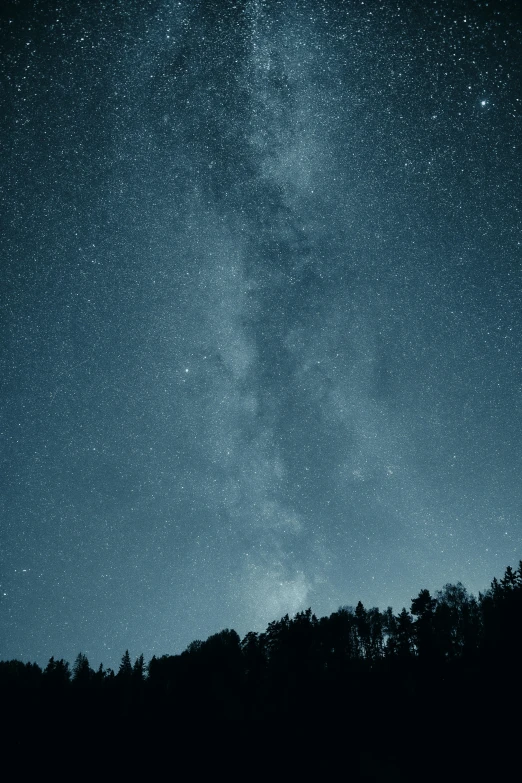 stars are glowing in the night sky over a hill