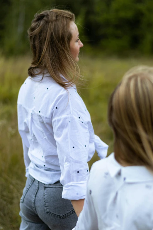 two women in white shirts walking through the woods