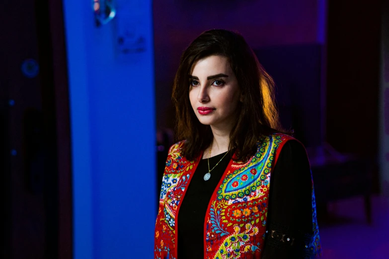 a woman standing in a dark room wearing a colorful outfit